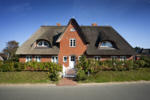 Häuser mit Reetdach prägen die Nordseeküste und sind sehr beliebt als Ferienhaus. © iStock